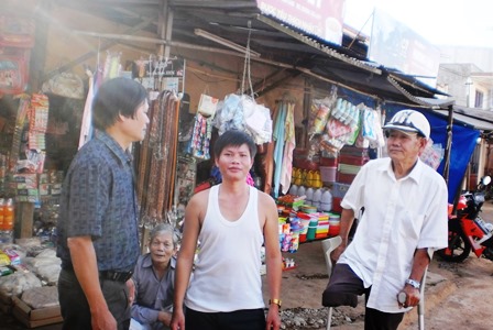 Anh Tuyên (người đứng phía bên trái) tuyên truyền, vận động bà con tiểu thương giữ gìn vệ sinh môi trường chợ.