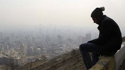 Một người Iran ngồi trên cao nhìn quang cảnh Tehran mờ mịt. (Ảnh: AP)