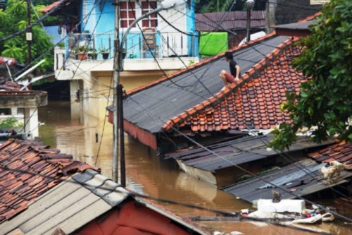 Người dân leo lên mái nhà để tránh nước lũ (Ảnh: AP)