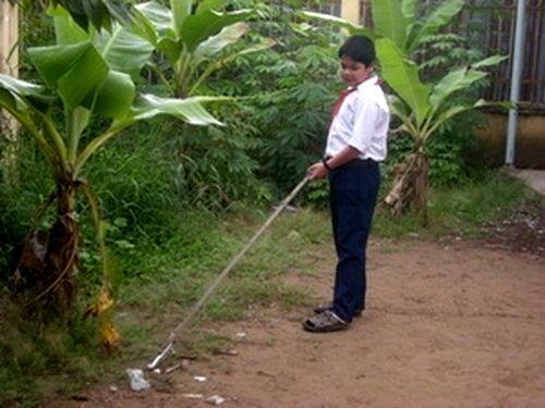 Em Hồ Lâm Hữu Luân sử dụng cây kẹp nhặt rác làm vệ sinh xung quanh trường