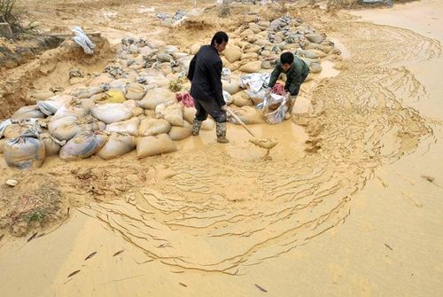 Những người công nhân đang lội bùn lao động tại một mỏ đất hiếm ở Trung Quốc (Ảnh: SAI)