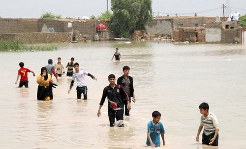 People cross a flooded area in Sheikh Saad district