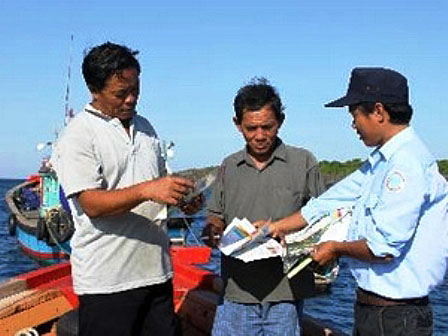 Cán bộ Khu bảo tồn biển đảo Cồn Cỏ phát tờ rơi tuyên truyền nâng cao nhận thức cho ngư dân (Ảnh: Hồ Cầu/TTXVN)