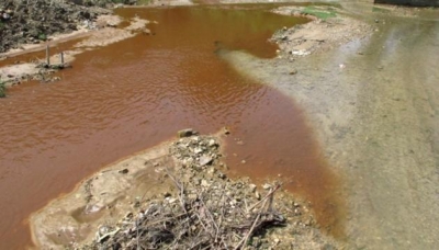 Nước từ mỏ vàng thôn Nà Diềm đổ xuống tạo thành con suối hai màu, chảy thẳng vào nguồn nước của khu dân cư (Ảnh: Nhân Dân)