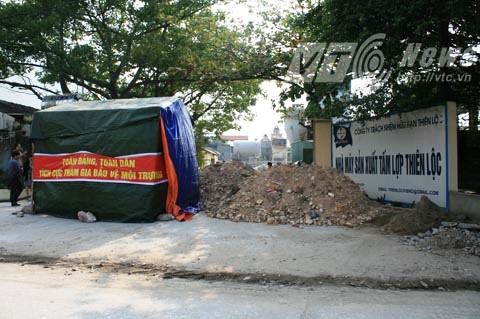 Đất đá, lều bạt dựng lên trước cổng nhà máy để phản đối kèm khẩu hiệu: "Toàn Đảng, toàn dân tích cực tham gia bảo vệ môi trường" (Ảnh Minh Khang/)