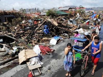 Người dân đi bên đống đổ nát sau bão Haiyan ở thành phố Tacloban, miền trung Philippines hôm 10/11 (Ảnh: AFP/TTXVN)