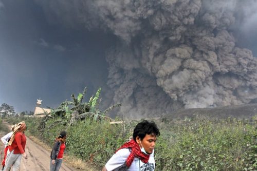 Dân làng và một phóng viên chuẩn bị để chạy khỏi vùng nguy hiểm khi núi Sinabung chuẩn bị phun trào nham thạch (Ảnh: AP)