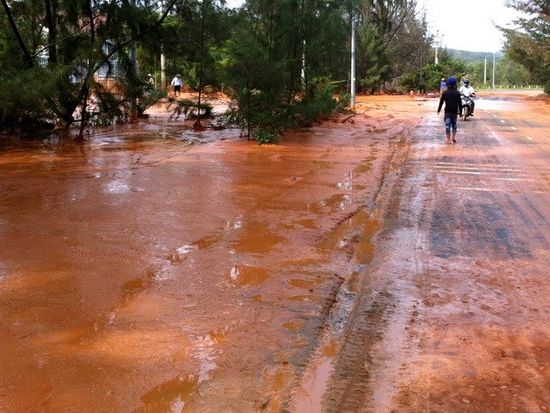 Sự cố vỡ bờ moong tại mỏ titan Suối Nhum khiến đất đỏ và bùn chảy tràn qua đường. (Ảnh: Nguyễn Thanh/TTXVN)