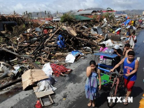 Người dân đi bên đống đổ nát sau khi bão Haiyan đi qua thành phố Tacloban, tỉnh Leyte, miền trung Philippines ngày 10/11/2013 (Ảnh: AFP/TTXVN)