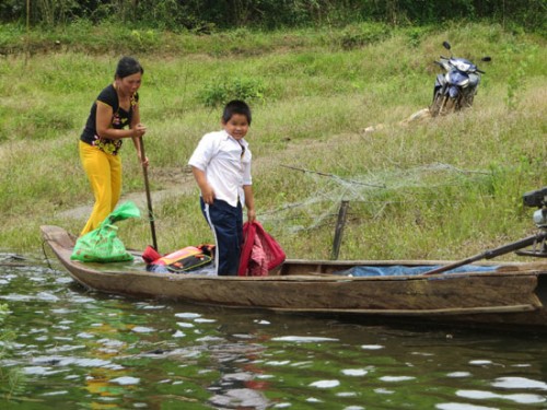 Hằng ngày, vợ anh Nguyễn Văn Diên phải chèo xuồng đưa đứa con nhỏ là Nguyễn Văn Mãi vào bờ rồi thuê người chở ra trung tâm xã Đác Som học chữ (Ảnh: Nhân Dân)