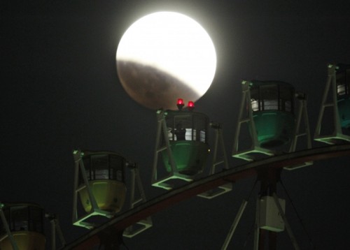 Mặt trăng bị che khuất một phần phía sau vòng đu quay Ferris ở Tokyo, Nhật Bản