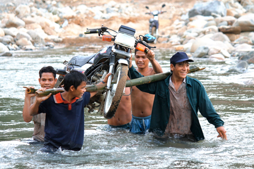 Thanh niên thôn O3 khiêng xe máy qua sông. (Ảnh: kinhtenongthon.com.vn)