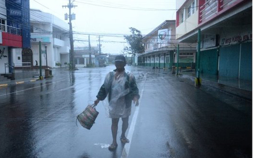 Một người đàn ông bước đi trong mưa gió ở Legazpi (Ảnh: AFP)