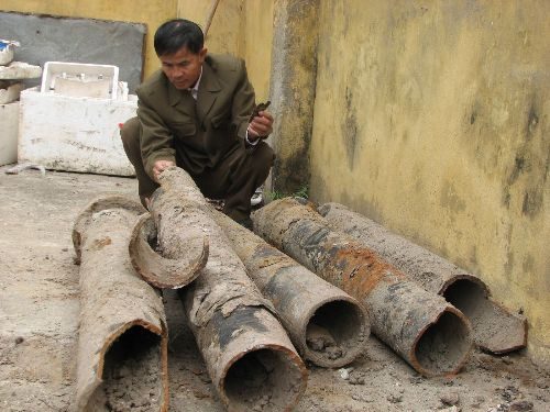 Ông Nguyễn Đình Tuấn - tổ dịch vụ nước sạch xã Vĩnh Quỳnh và những đoạn ống nước bị vỡ. (Ảnh: Kinh tế & Đô thị Điện tử)