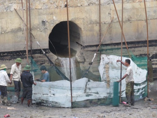 Công nhân nhà máy đang thu dọn lòng sông ô nhiễm