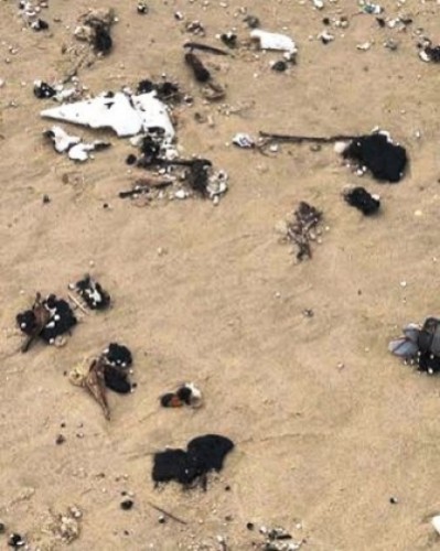 Dầu vón cục trôi dạt vào bờ biển tỉnh Quảng Trị. (Ảnh: Nhân Dân)