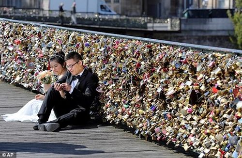 Một cặp đôi chụp ảnh cưới trên "cầu tình yêu" Pont des Arts. (Ảnh: Dân Việt)