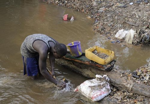 Một thanh niên làm việc bên dòng nước đục. (Ảnh: AFP)