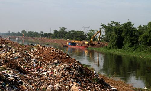 Dòng sông đang được nạo vét và mở rộng để khơi thông dòng chảy, tuy nhiên dọc bờ sông người dân vẫn đổ rác thành bãi. (Ảnh: Báo Tin tức)