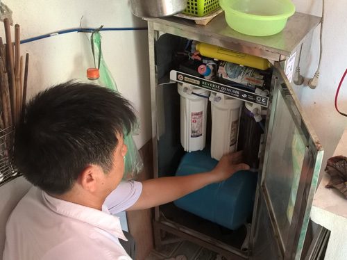 Ông Dương Văn Khơ đang phải thay củ lọc máy lọc nước bị đen quánh sau 1-2 tháng sử dụng.