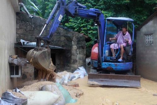 Lực lượng chức năng dùng máy xúc bao tải cát để ngăn nước không tràn vào ngập nhà dân tại phường Cao Thắng, Thành phố Hạ Long. (Ảnh: Minh Quyết/TTXVN)