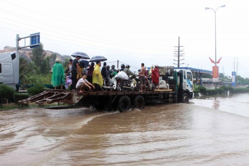 Mưa lớn gây gập úng đoạn ngã tư Cái Lân (Thành phố Hạ Long), người dân phải di chuyển qua bằng xe tải (ảnh chụp lúc 11h ngày 28/7). (Ảnh: Minh Quyết/TTXVN)