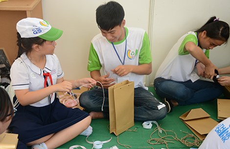 Tình nguyện viên đang hướng dẫn các em nhỏ làm túi xách từ vật liệu giấy tái chế tại một chương trình do Sở TN&MT TP.HCM tổ chức (Ảnh: NC)