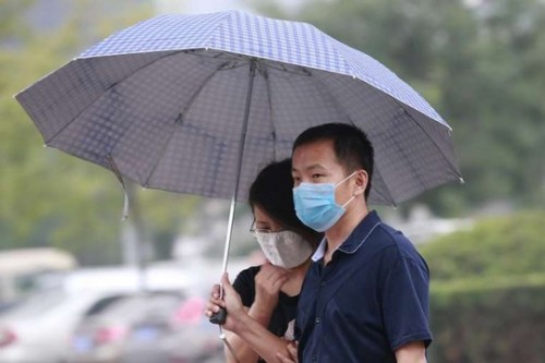 Một cặp đôi che dù đi dưới mưa ở TP Thiên Tân ngày 18-8 (Ảnh: Reuters)