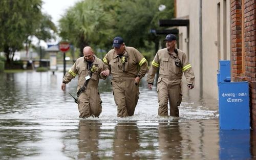 Lực lượng cứu hộ băng qua con đường ngập lụt. (ảnh: AP).
