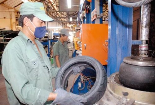 Công nhân sử dụng thiết bị an toàn lao động tránh tiếp xúc trực tiếp sản phẩm cao su tại một nhà máy (Ảnh: Cao Thăng/SGGP)