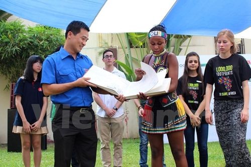 Đại sứ tê giác Nam Phi trao cuốn sách bảo vệ tê giác cho đại diện Đoàn Thanh niên Cộng sản Hồ Chí Minh (Ảnh: Hùng Võ/Vietnam+)
