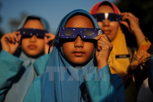 Các học sinh Malaysia đeo kính để quan sát hiện tượng nhật thực một phần ở Kuala Lumpur ngày 9/3. (Nguồn: AFP/TTXVN)