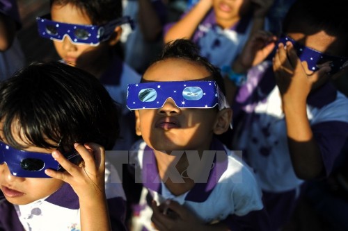 Các học sinh Malaysia đeo kính để quan sát hiện tượng nhật thực một phần ở Kuala Lumpur ngày 9/3. (Nguồn: AFP/TTXVN)