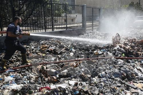 Nhân viên cứu hỏa phun nước dập các đám cháy sau khi người biểu tình đốt rác thải bị ứ đọng trên một đường phố ở Beirut (Nguồn: AFP/TTXVN)