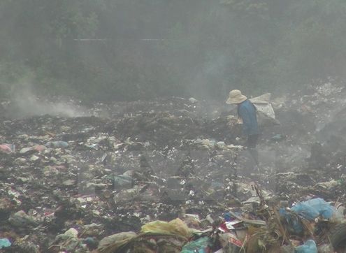 Rác vẫn âm ỉ cháy tại bãi rác xã Trường Thủy khiến khói bụi mù mịt (Ảnh: Đức Thọ/TTXVN)