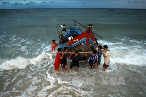 Kéo thuyền vào bãi sau một ngày đánh bắt ngoài khơi (Ảnh: Tuấn Anh/TTXVN)