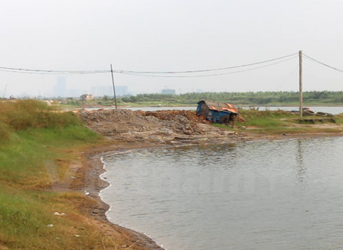 Bùn thải đổ ven đường tràn xuống nước. (Ảnh: MM/Vietnam+)