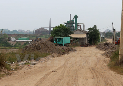  Bùn thải đổ ven đường đê sông Hồng tại xã Đại Mạch, huyện Đông Anh. (Ảnh: MM/Vietnam+)