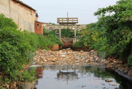 Lượng lớn rác thải ùn ứ, tồn đọng trước cửa cống nối bãi rác khổng lồ với kênh dẫn nước đổ trực tiếp ra cảng Tân Sơn. (Ảnh: Xuân Tiến/TTXVN)